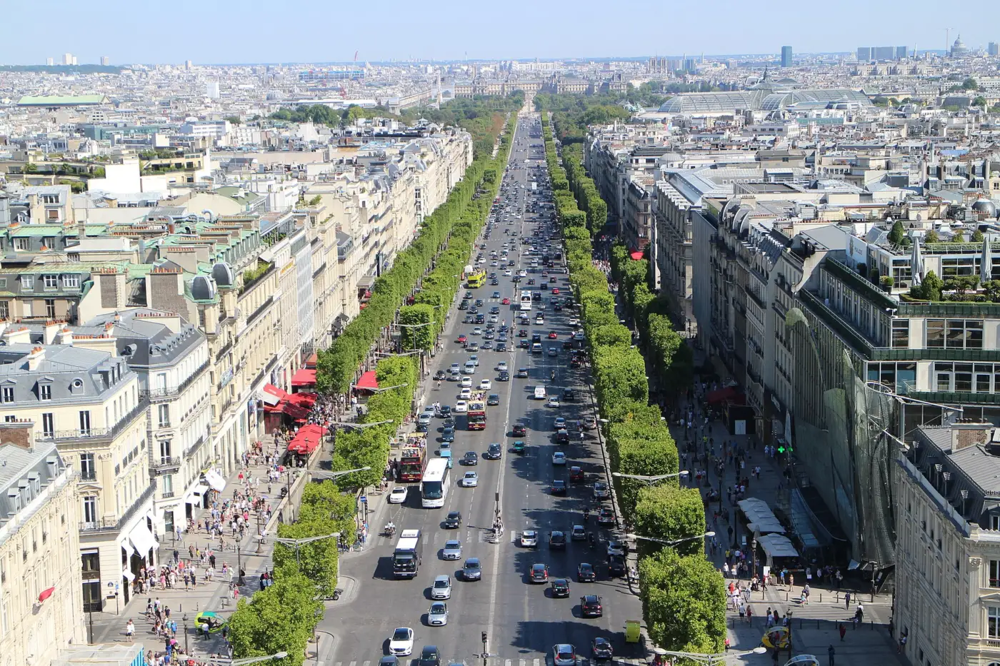 L'avenue des Champs-Élysées vue depuis le sommet de l'Arc de Triomphe, bordée d'arbres, avec la circulation au centre