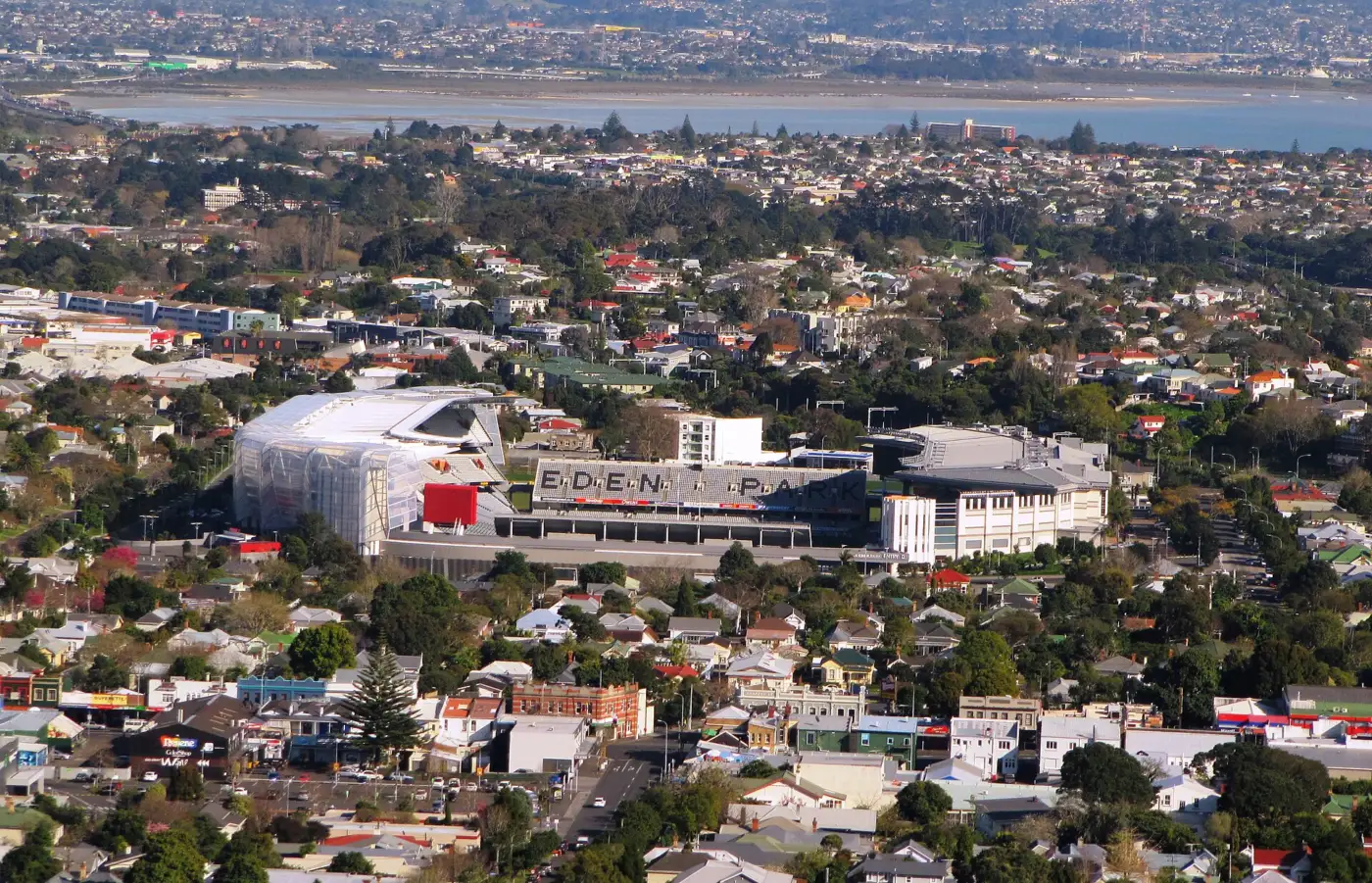 Le stade de l'Eden Park à Auckland vu de loin depuis le mont Eden, au milieu des maisons, avec l'inscription Eden Park sur la tribune