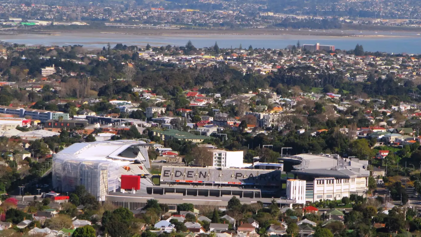 Le stade de l'Eden Park à Auckland vu de loin depuis le mont Eden, au milieu des maisons, avec l'inscription Eden Park sur la tribune