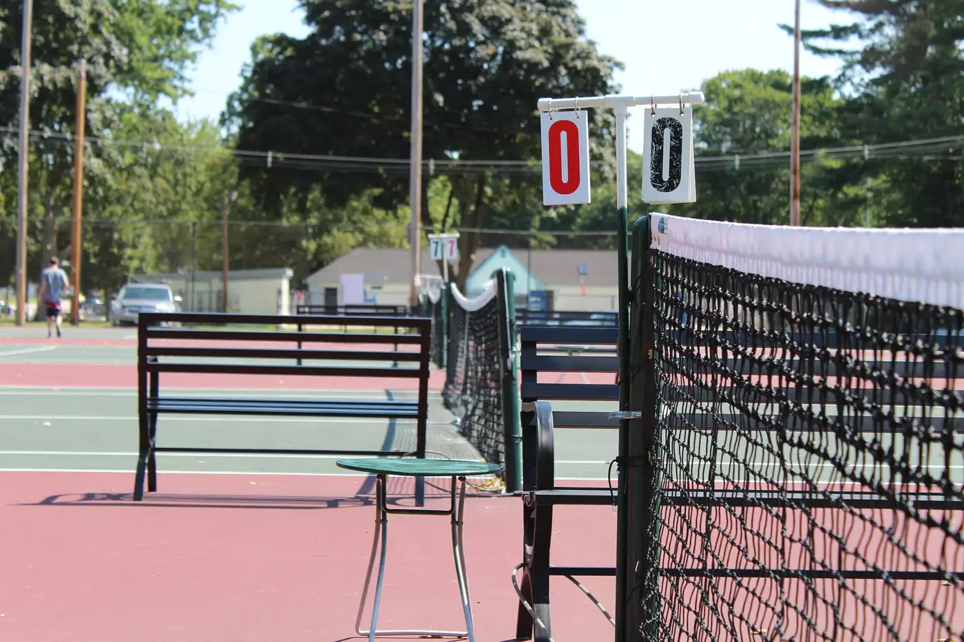 Marqueurs de score à cartes accrochés au poteau d'un filet de tennis, sur des courts publics en plein air