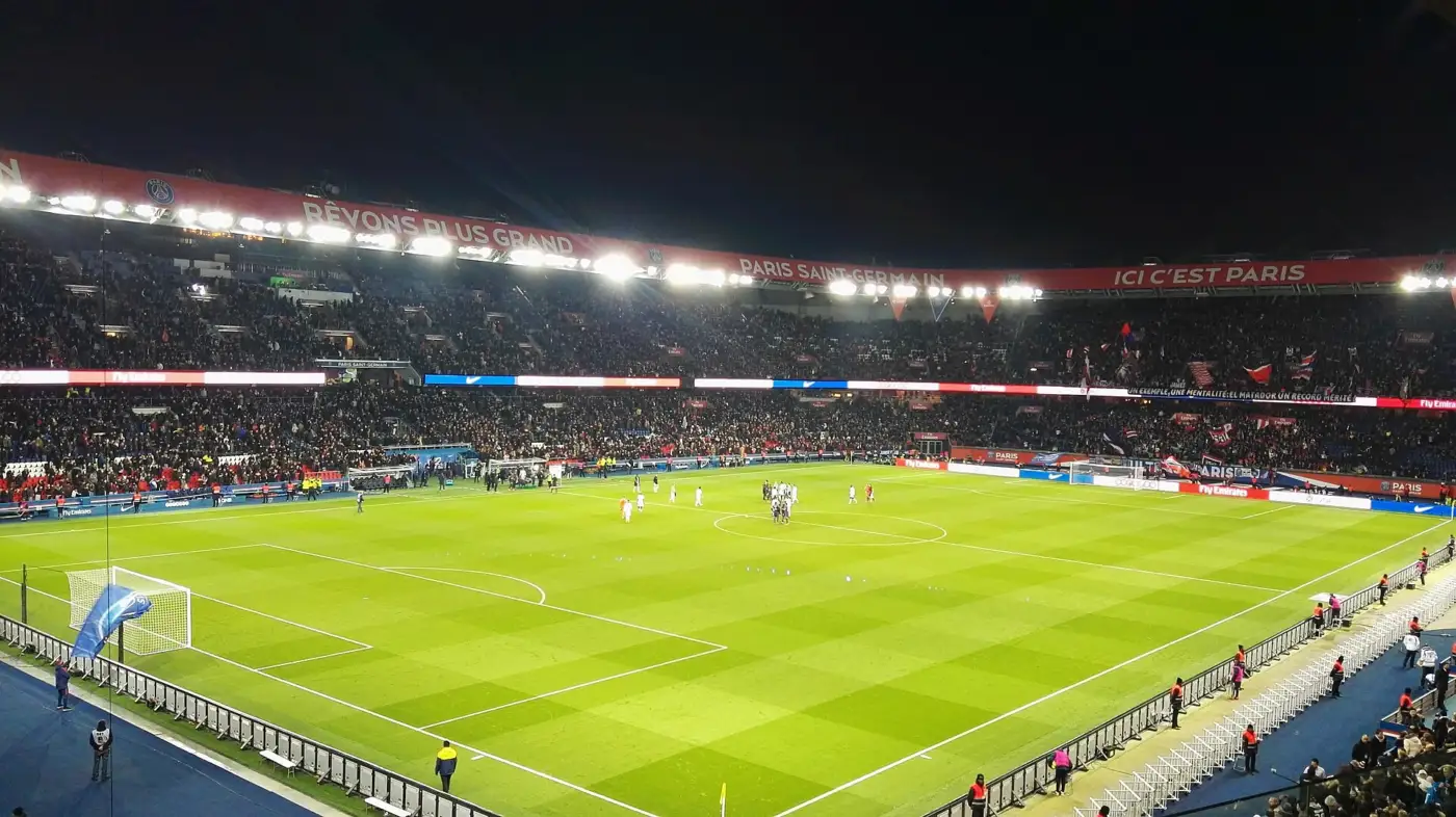 Pelouse et tribunes pleines du Parc des Princes éclairé de nuit pendant un match de Ligue 1