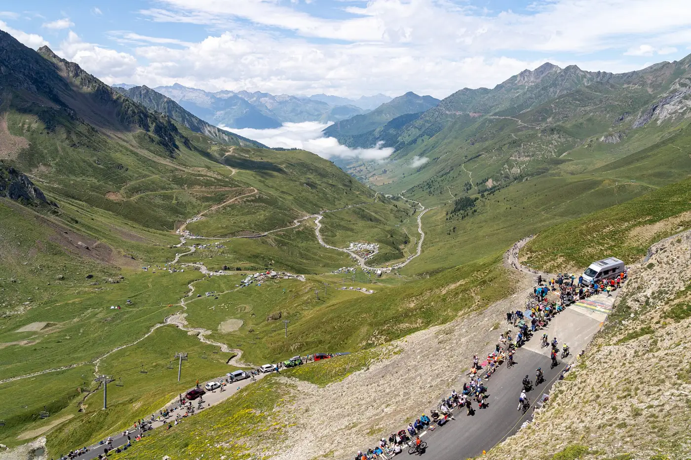 Vue depuis le sommet du col du Tourmalet le jour de la 14e étape du Tour de France 2024, spectateurs massés le long de la route et vallée pyrénéenne en contrebas