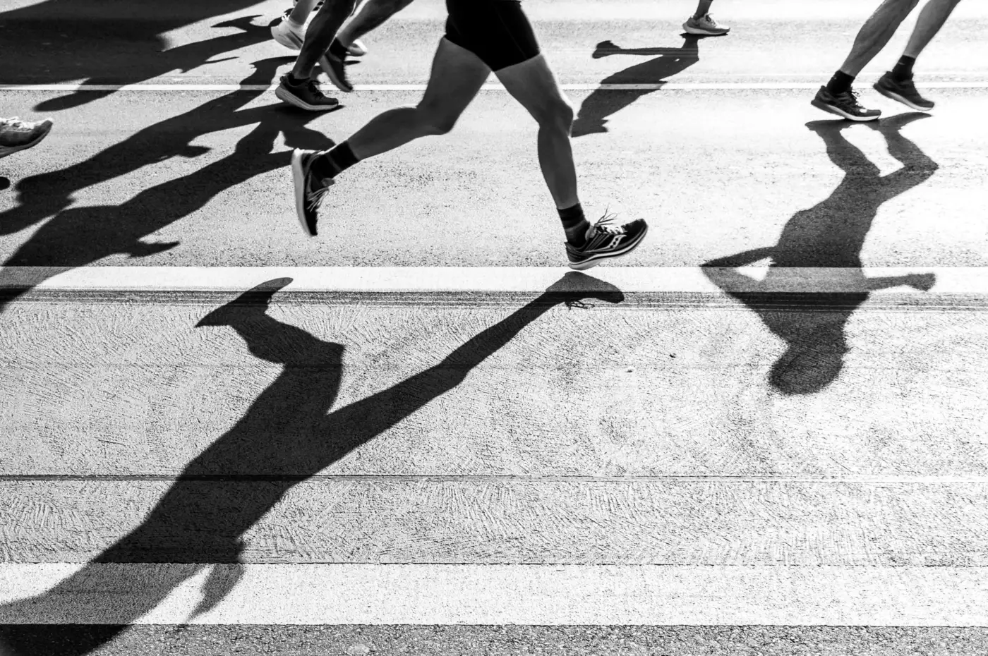 Ombres de coureurs projetées sur la chaussée pendant une course sur route, photo en noir et blanc